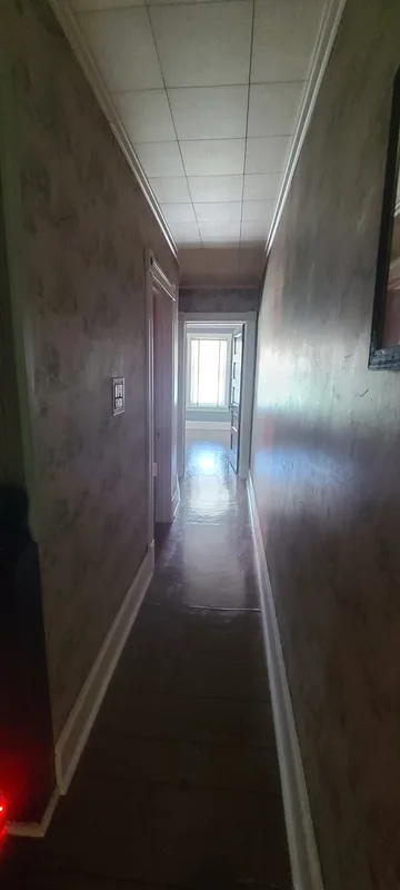 Hallway from stairs to the front bedroom. Vintage wallpaper, vinyl floors, sunlight glinting off the floors