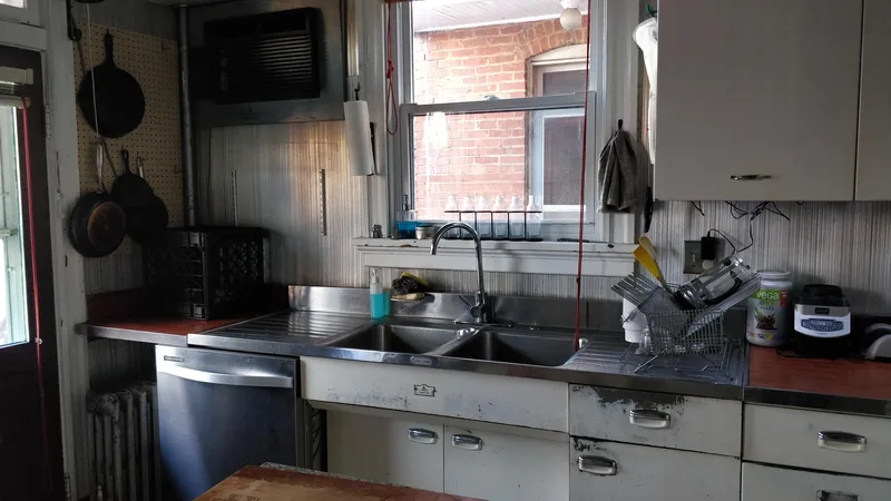 Kitchen sink, silver backsplash, white cabinets, white trim, silver dishwasher. Window above sink